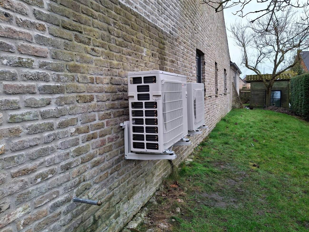 Twee buitenunits airco op wandbeugel tegen een gevel